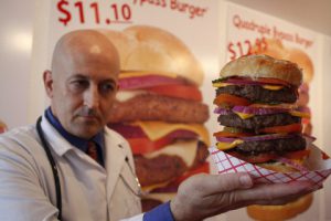 Heart Attack Grill owner Jon poses with a quadruple bypass cheese burger in Chandler, Arizona June 17, 2009. The restaurant is known for its hospital theme and triple and quadruple bypass burgers. REUTERS/Joshua Lott (UNITED STATES) - RTR24RS3